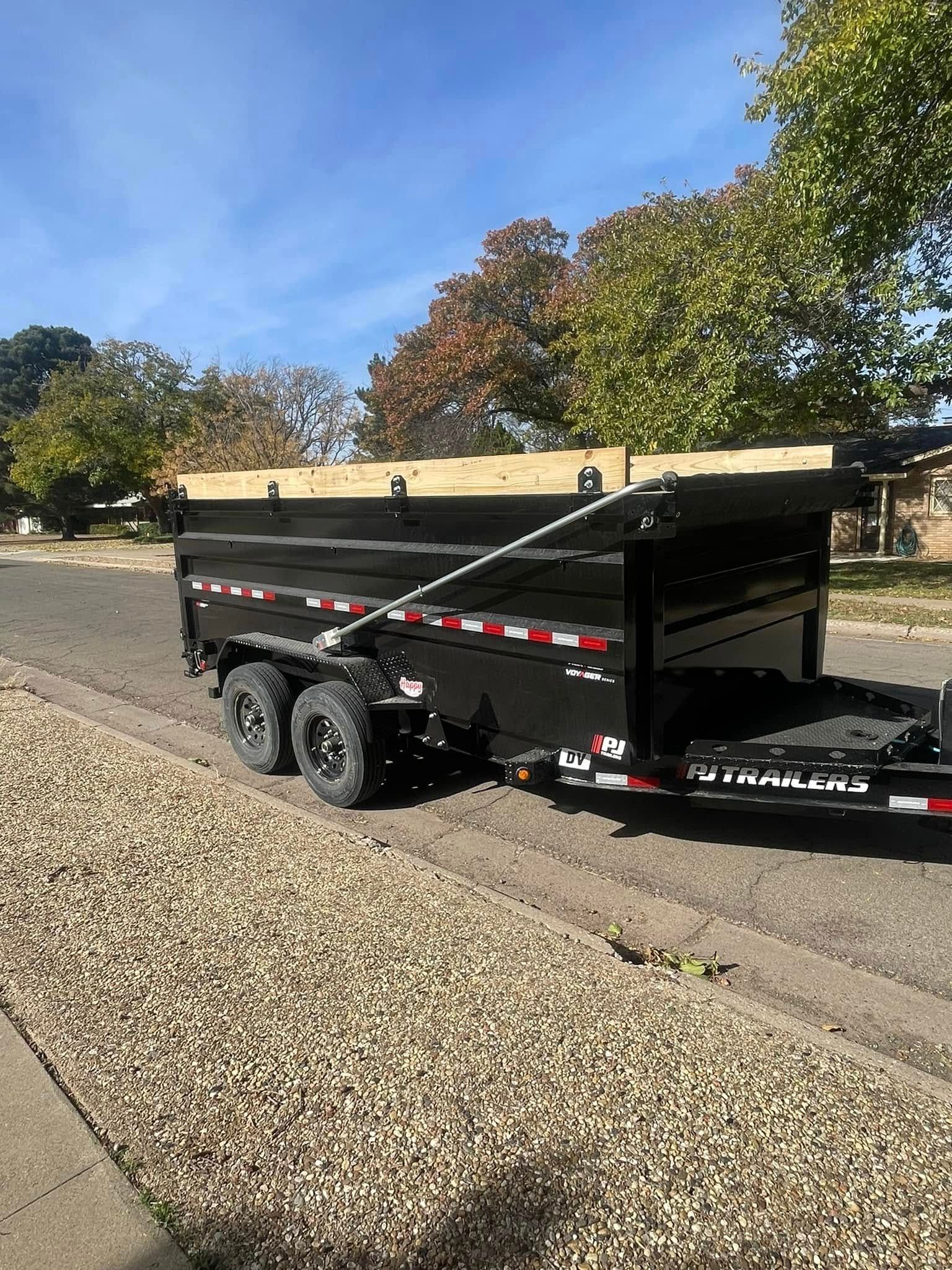 A dump trailer is parked on the side of the road.