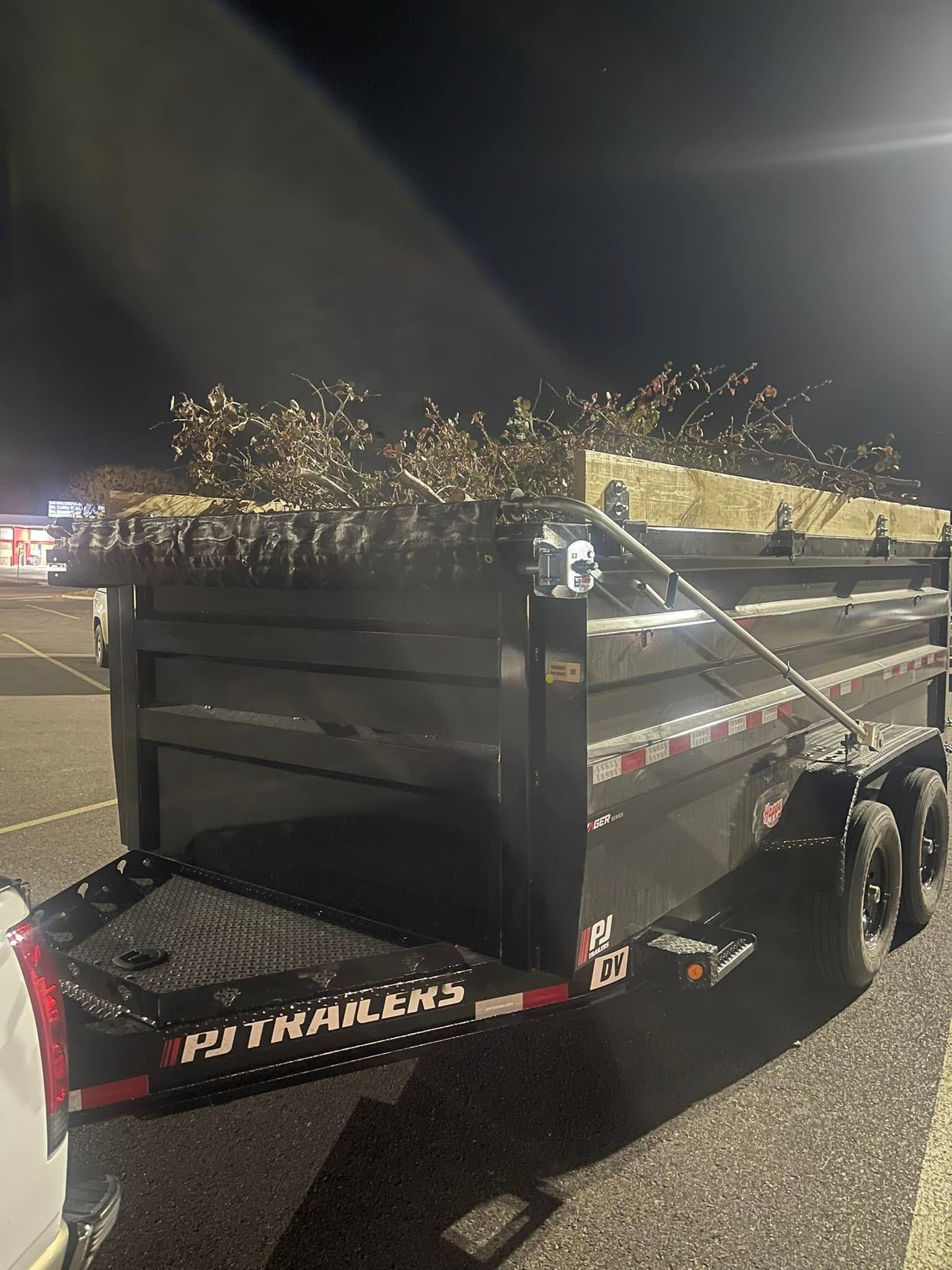 A dump trailer is parked in a parking lot at night.