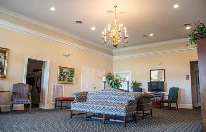 A living room with a couch , chairs , and a chandelier.