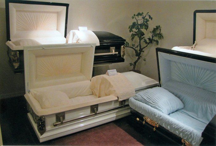 Two coffins are open in a room with a tree in the background