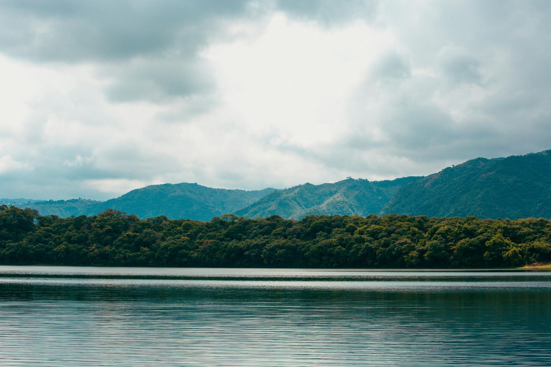 A lake with mountains in the background and trees on the shore.