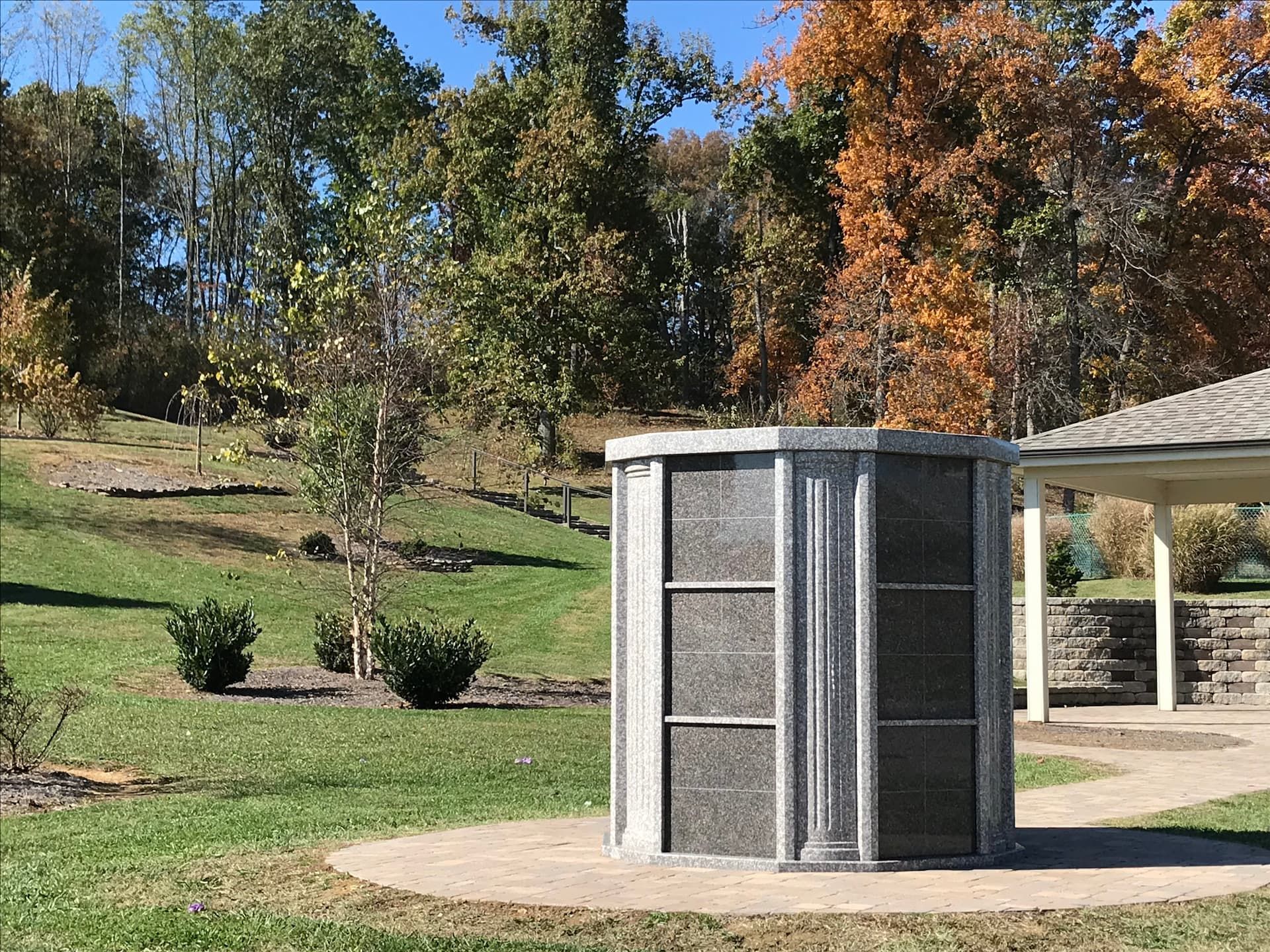 A small building in the middle of a park with trees in the background.