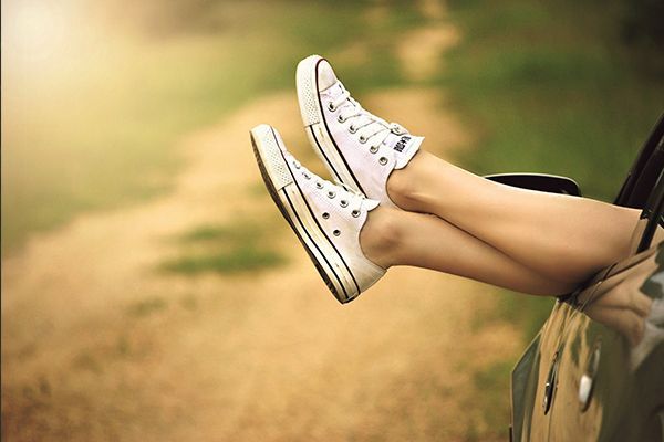 a woman 's feet are sticking out of the window of a car .