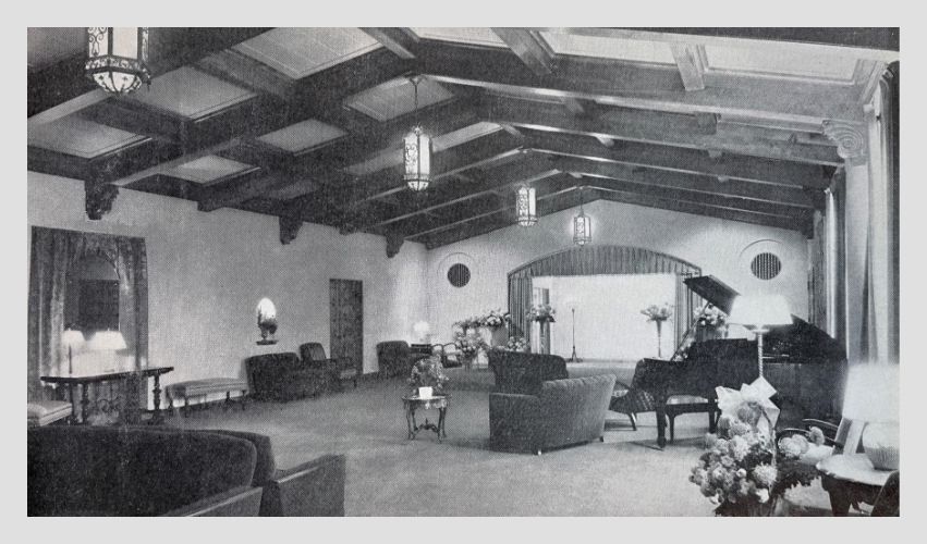 A black and white photo of a living room with a piano