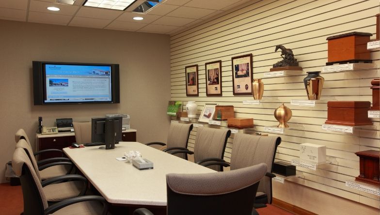 A conference room with a large table and chairs and a flat screen tv on the wall.