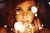 A woman is holding a string of lights in front of her face.