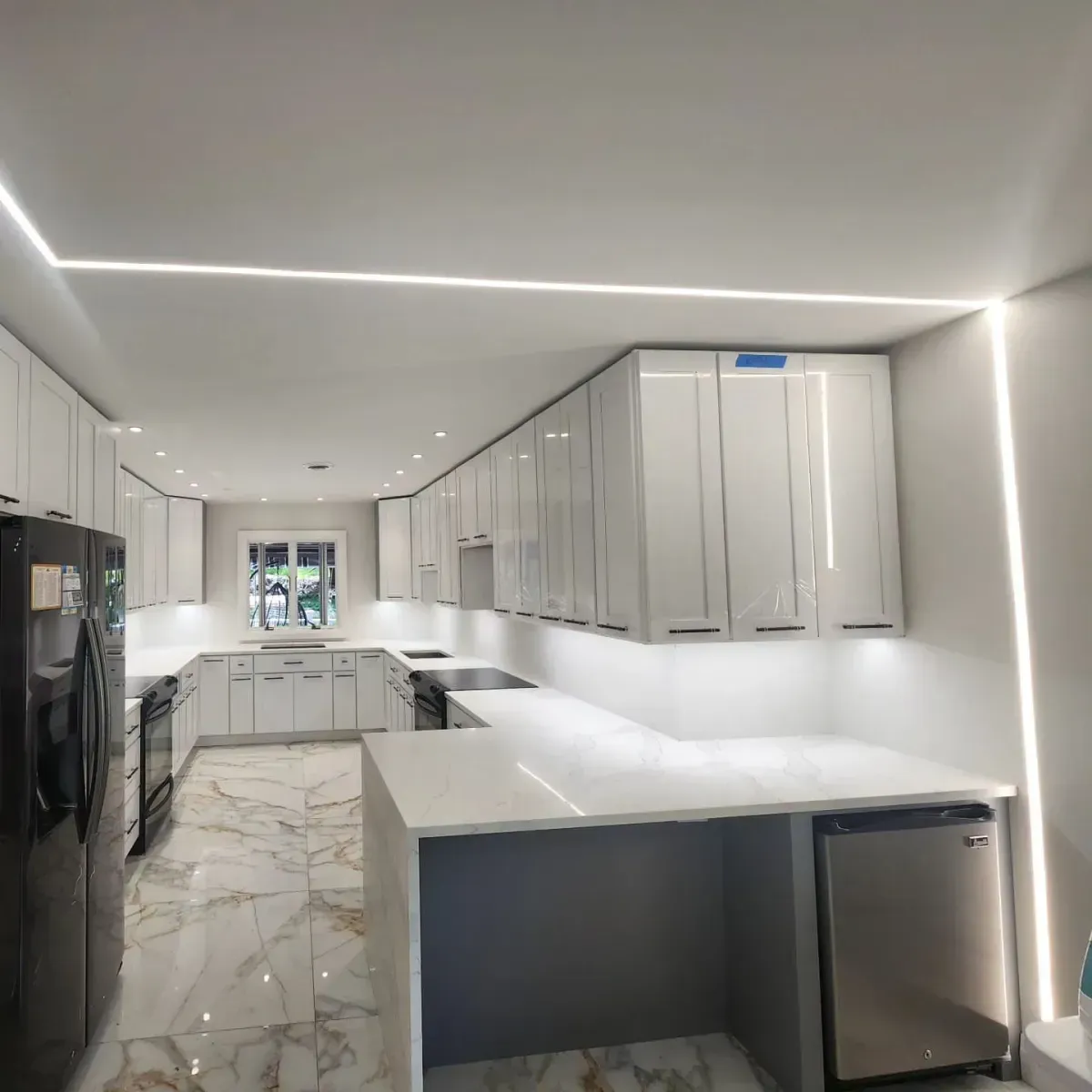A kitchen with white cabinets and a black refrigerator