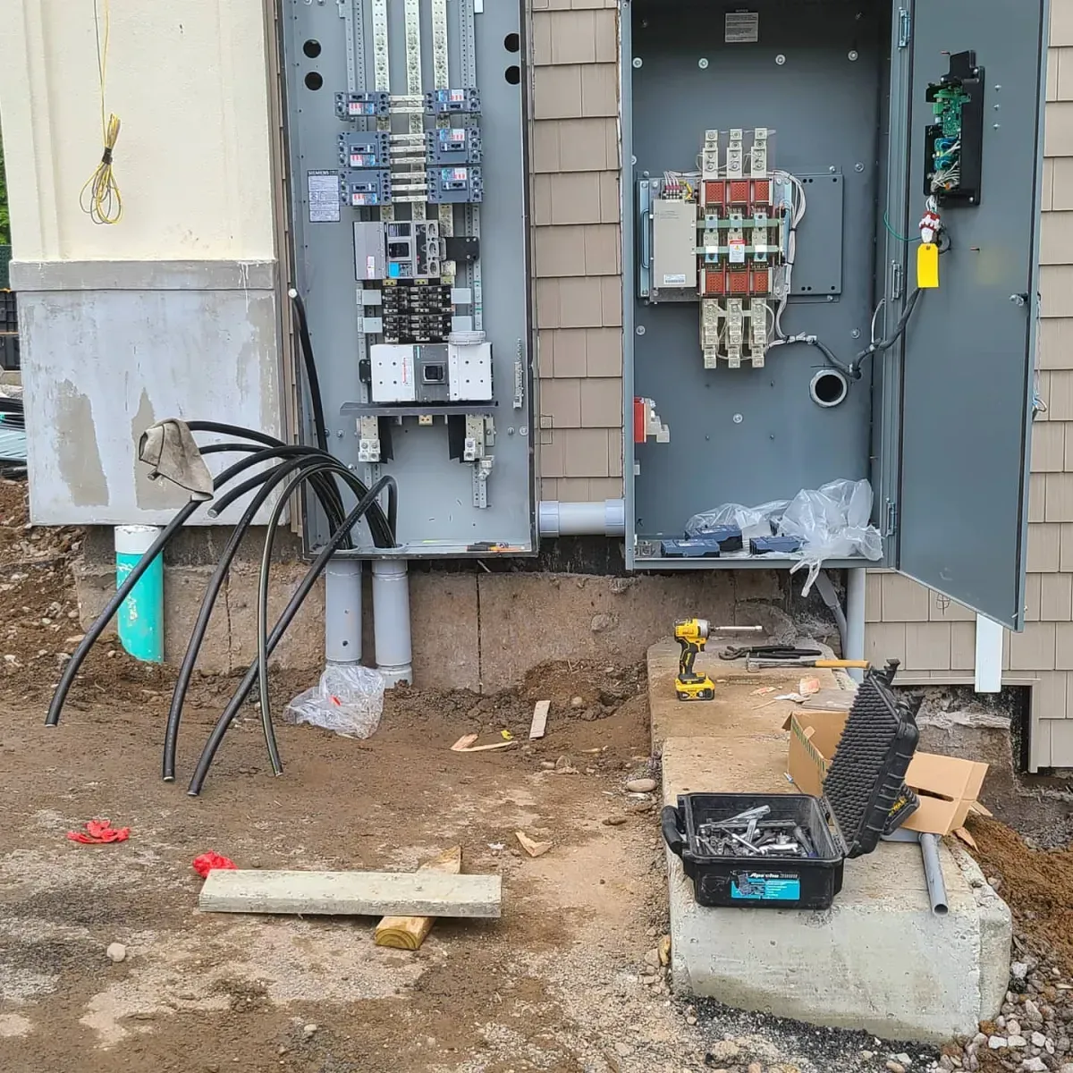 A electrical box is being installed on the side of a building.