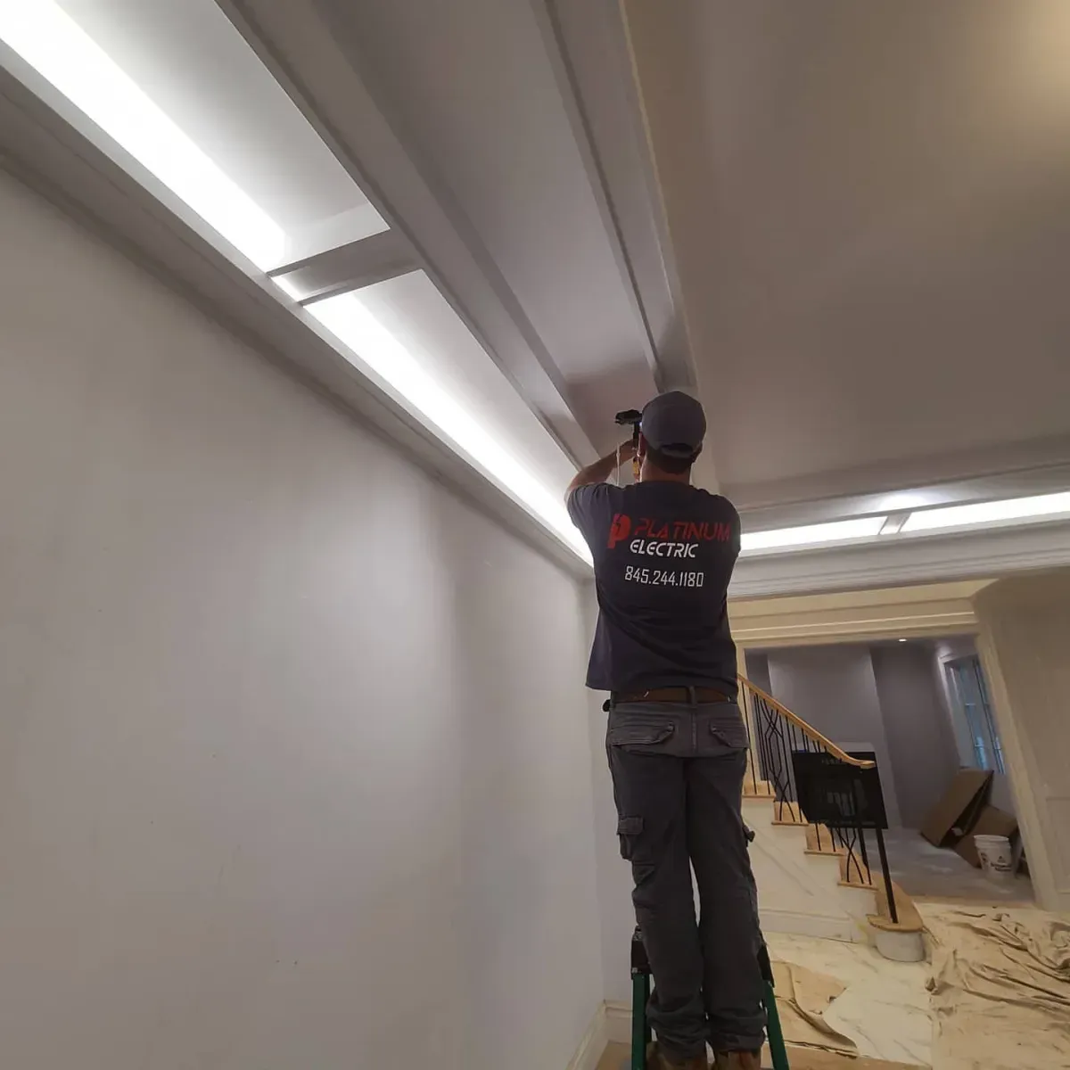 A man is standing on a ladder working on a ceiling.