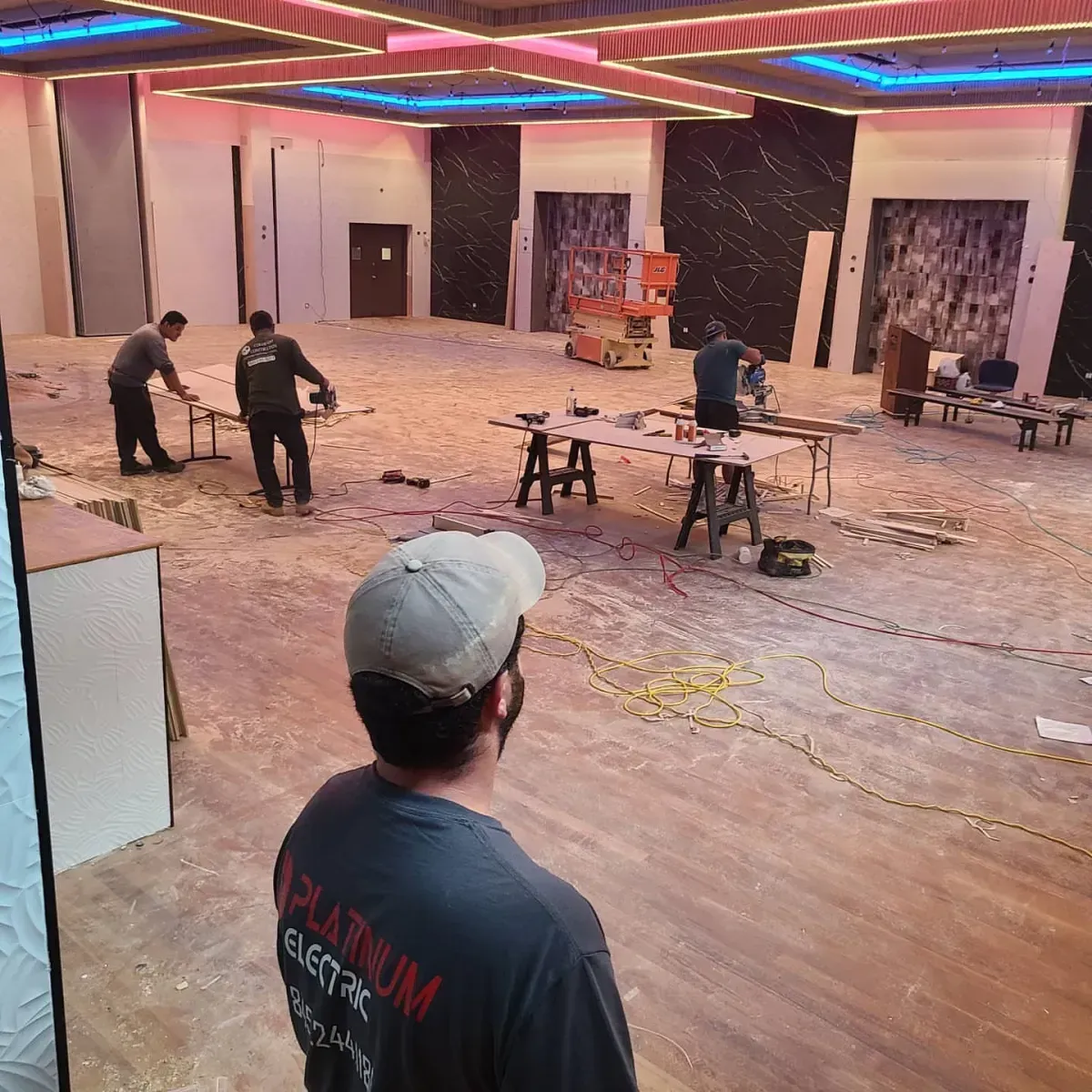A man in a platinum shirt is standing in a large room.