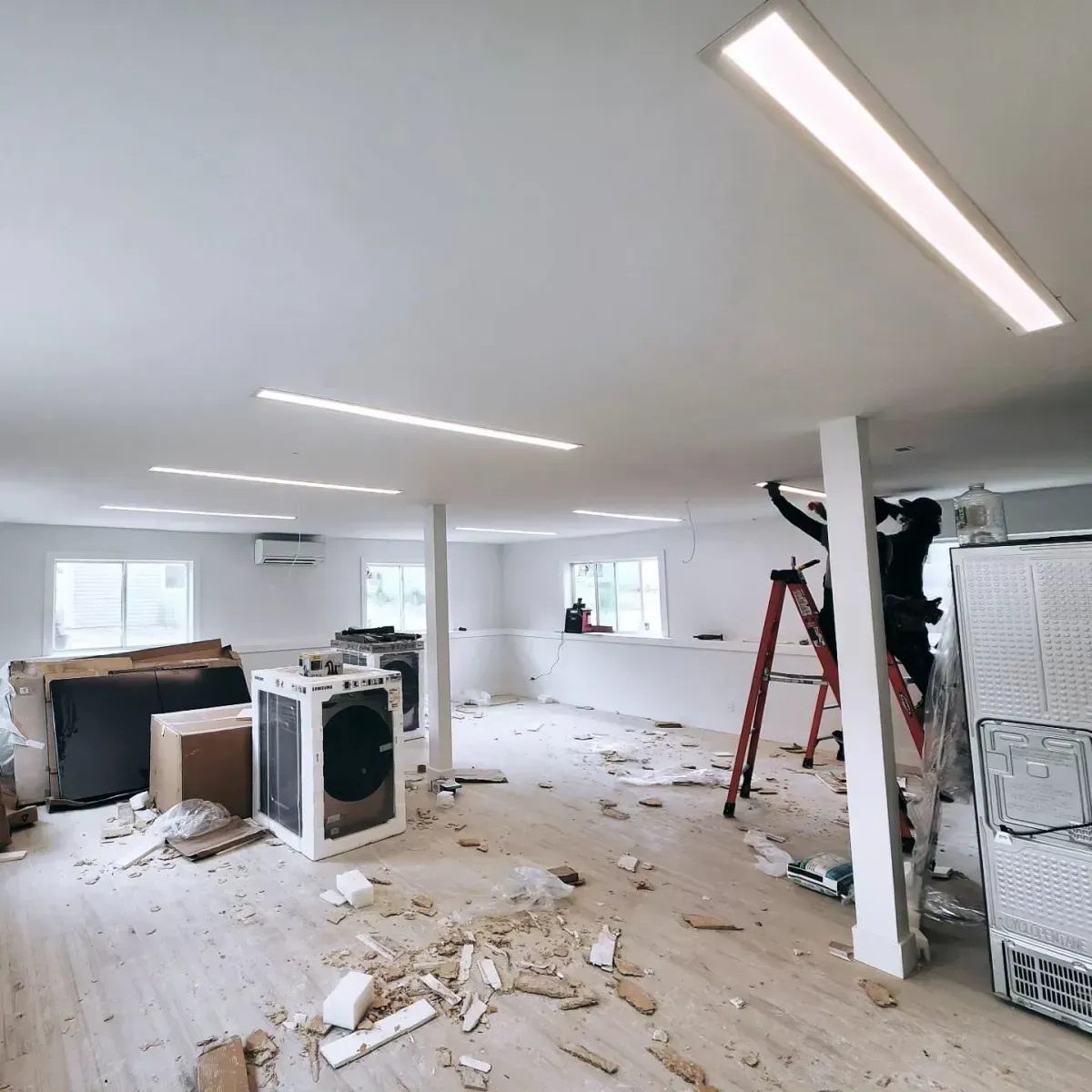 A man is standing on a ladder in a room that is being remodeled.