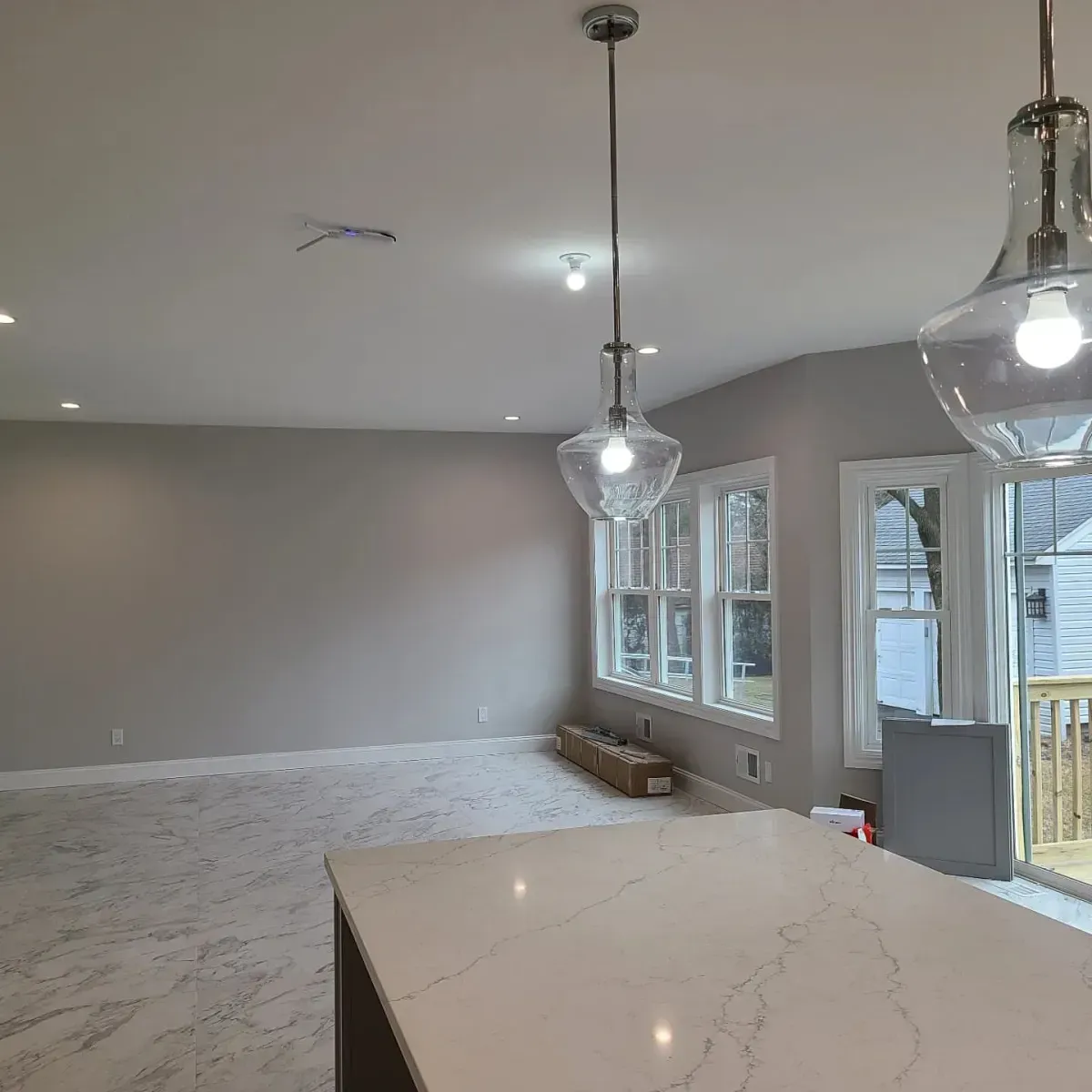 A large empty room with a lot of windows and lights hanging from the ceiling.