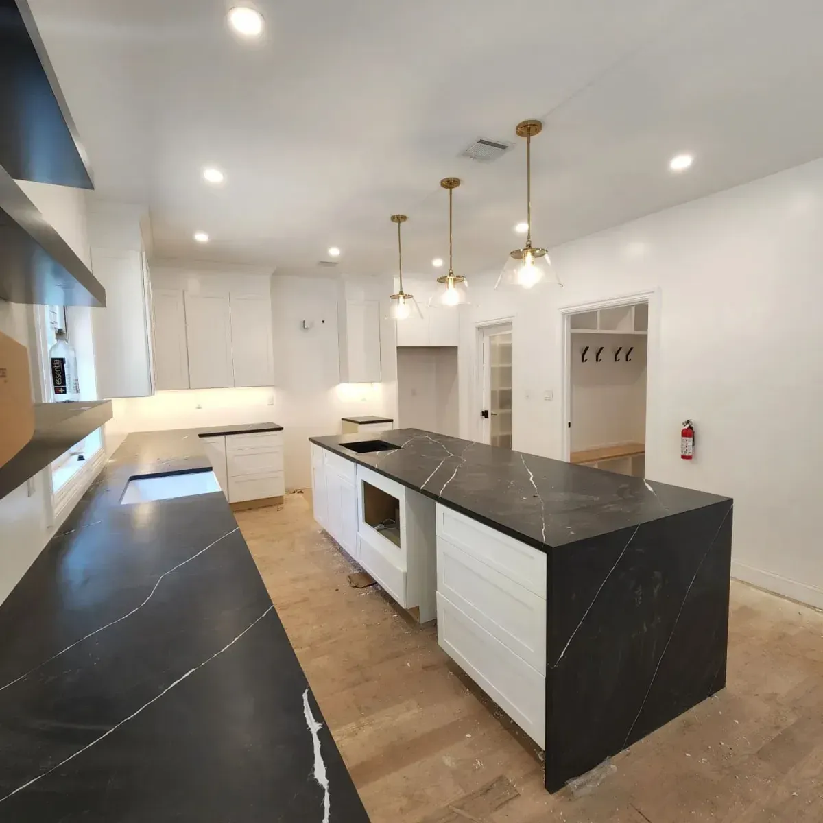 A kitchen with black counter tops and white cabinets