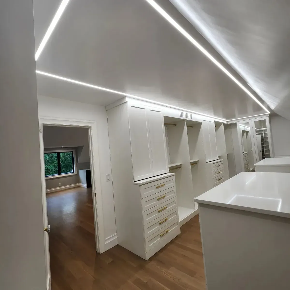 A walk in closet with lots of white cabinets and drawers