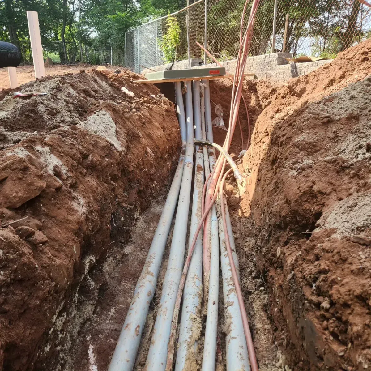 A bunch of electrical wires are being installed in a trench.