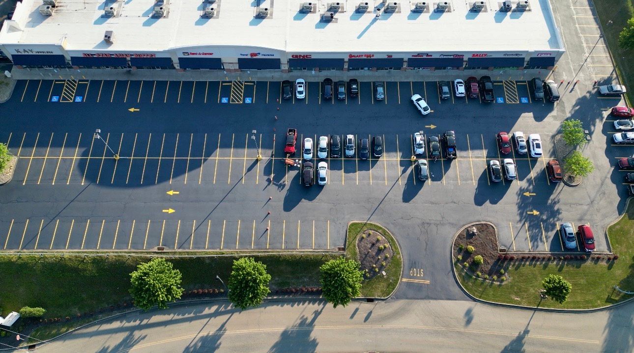 An aerial view of a parking lot with a building in the background.