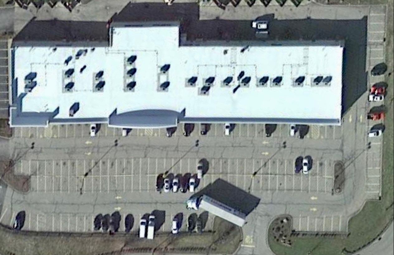 An aerial view of a large building with a parking lot in front of it.
