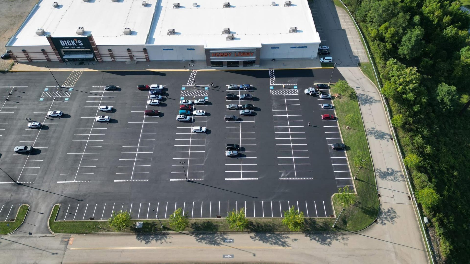 An empty parking lot with trees in front of a building.