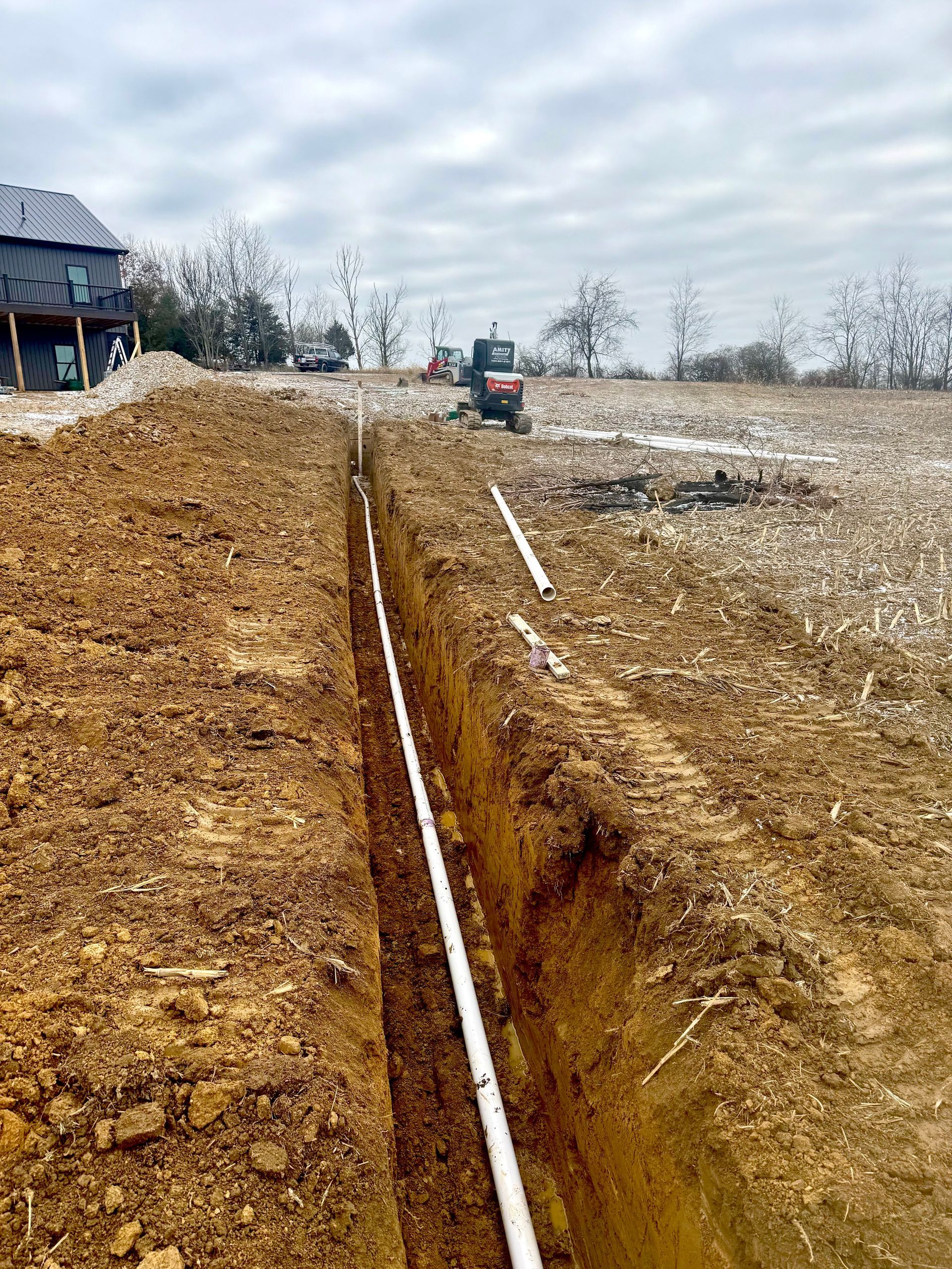 A close up of a pipe in the dirt with a hose attached to it.