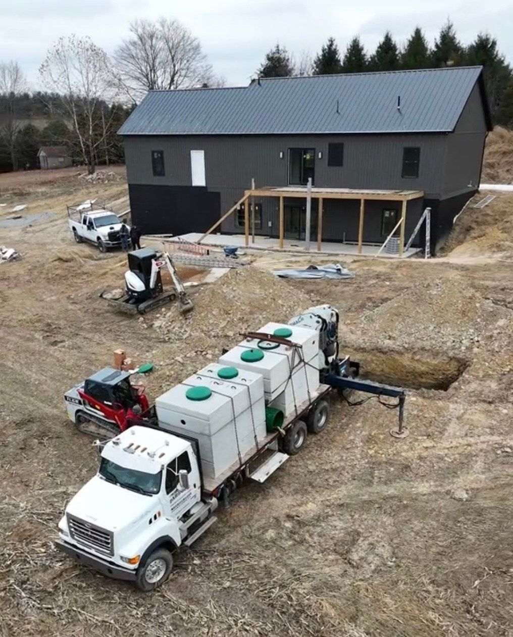 A large black septic tank is sitting in the dirt.