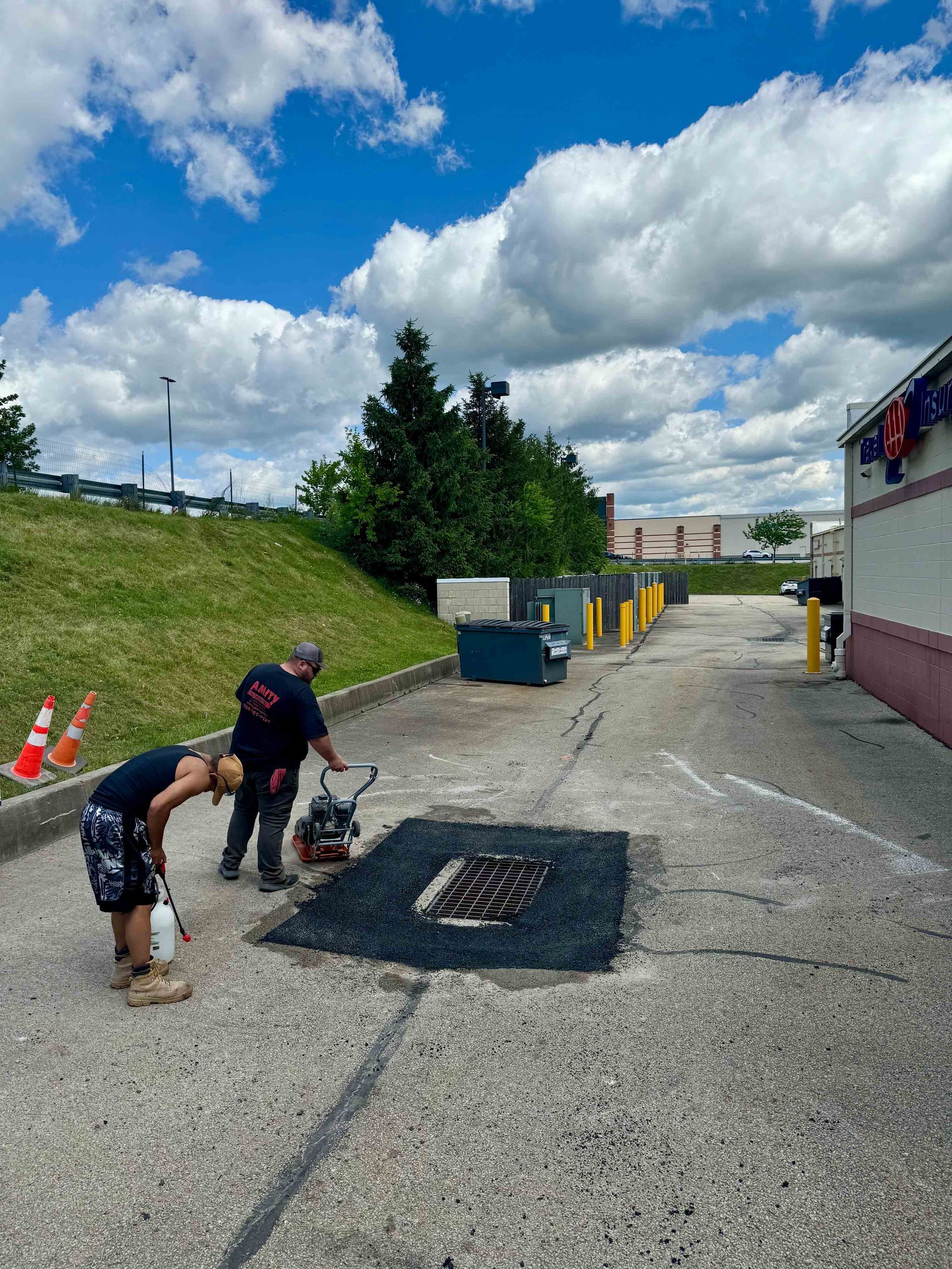 A person is applying black paint to a concrete surface with a brush.