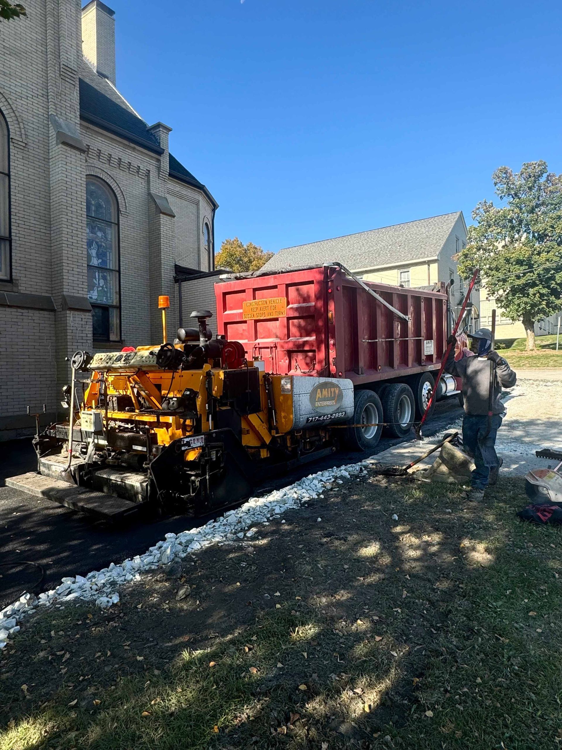 A white garage with a black driveway in front of it.