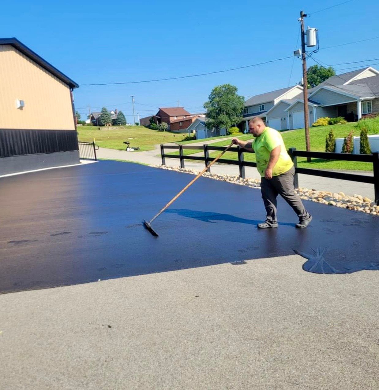 A person is standing on a sidewalk holding a tool.