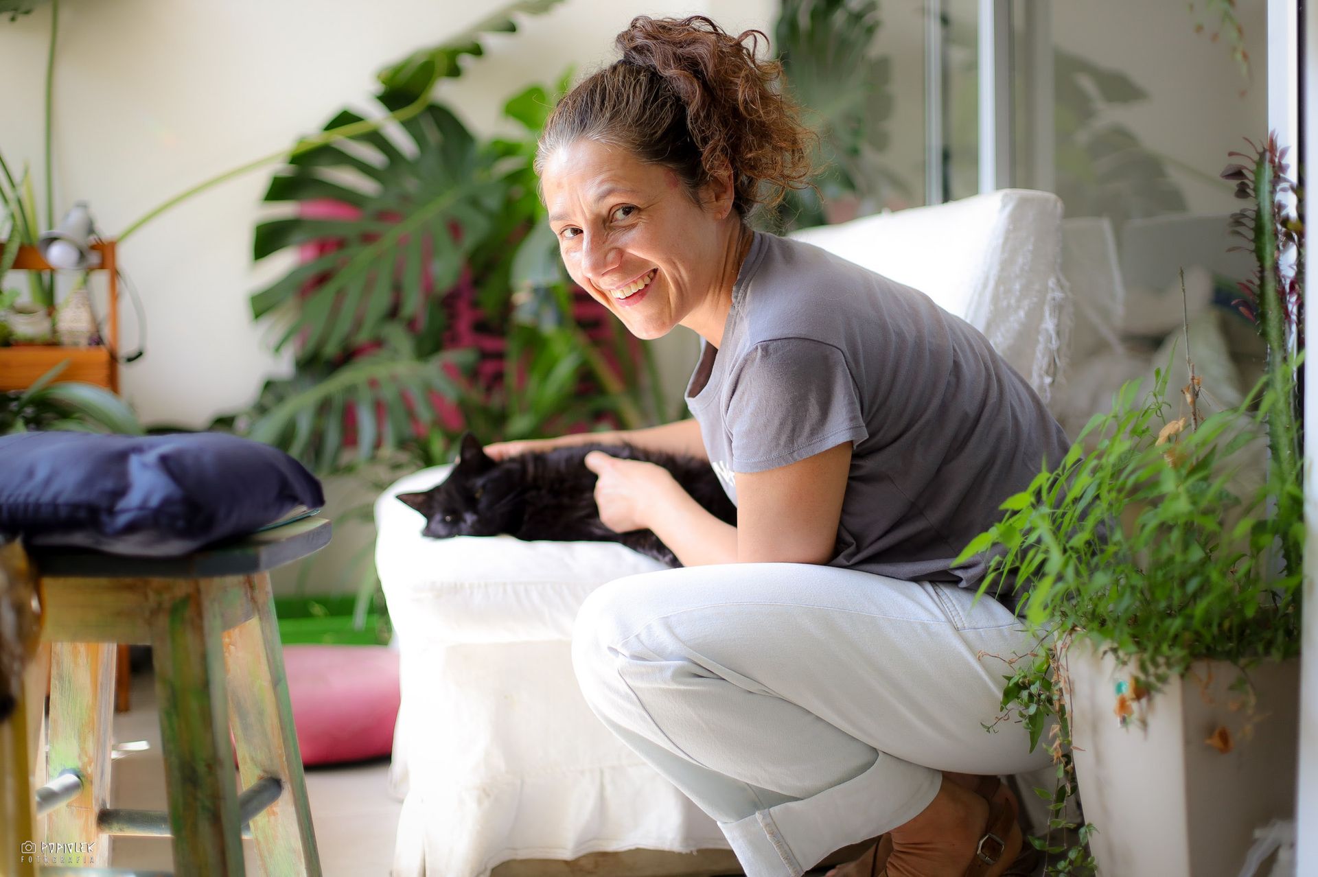 Una mujer está arrodillada con un gato negro en su regazo.