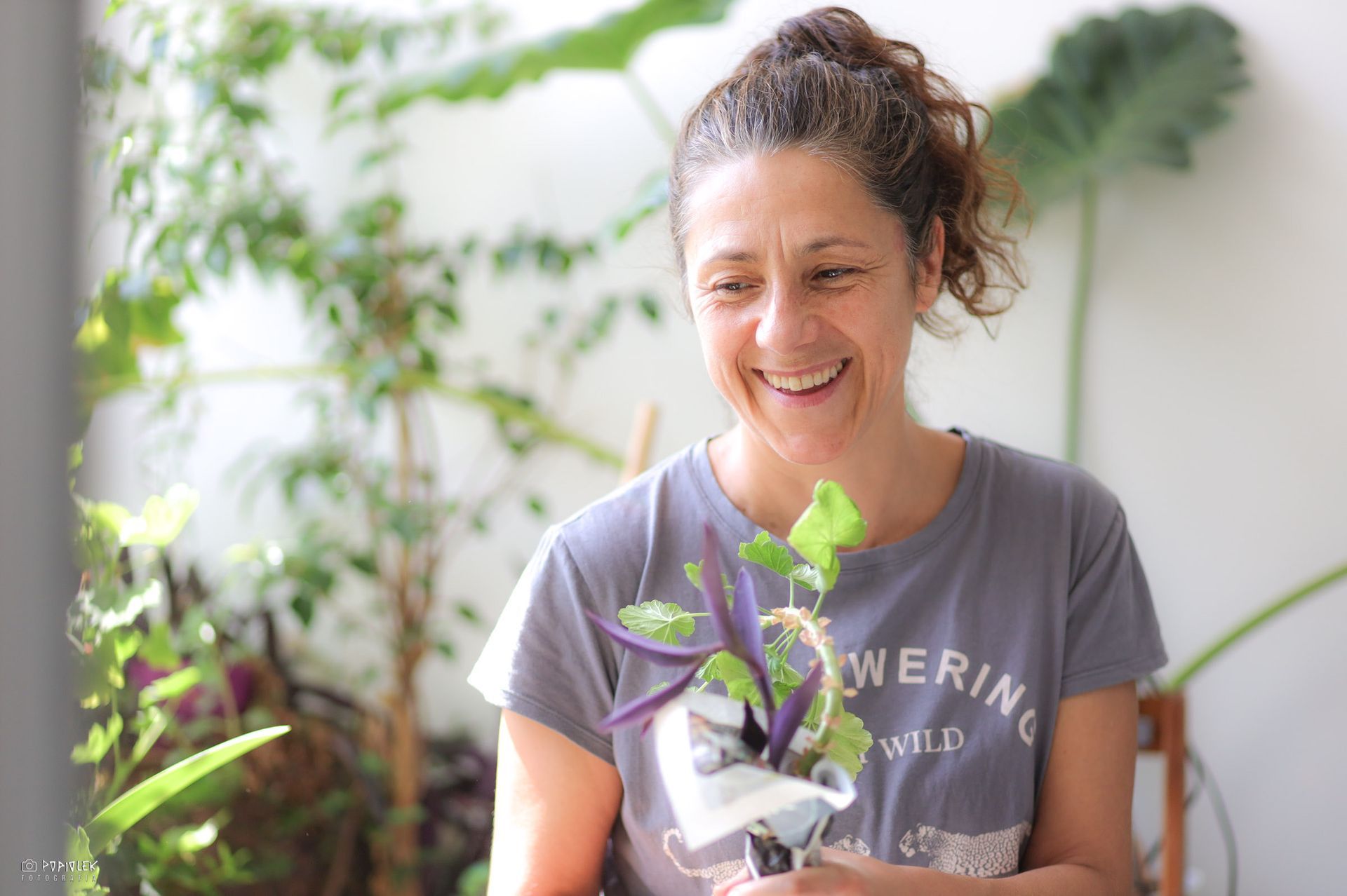 Una mujer sonríe mientras sostiene una planta en sus manos.
