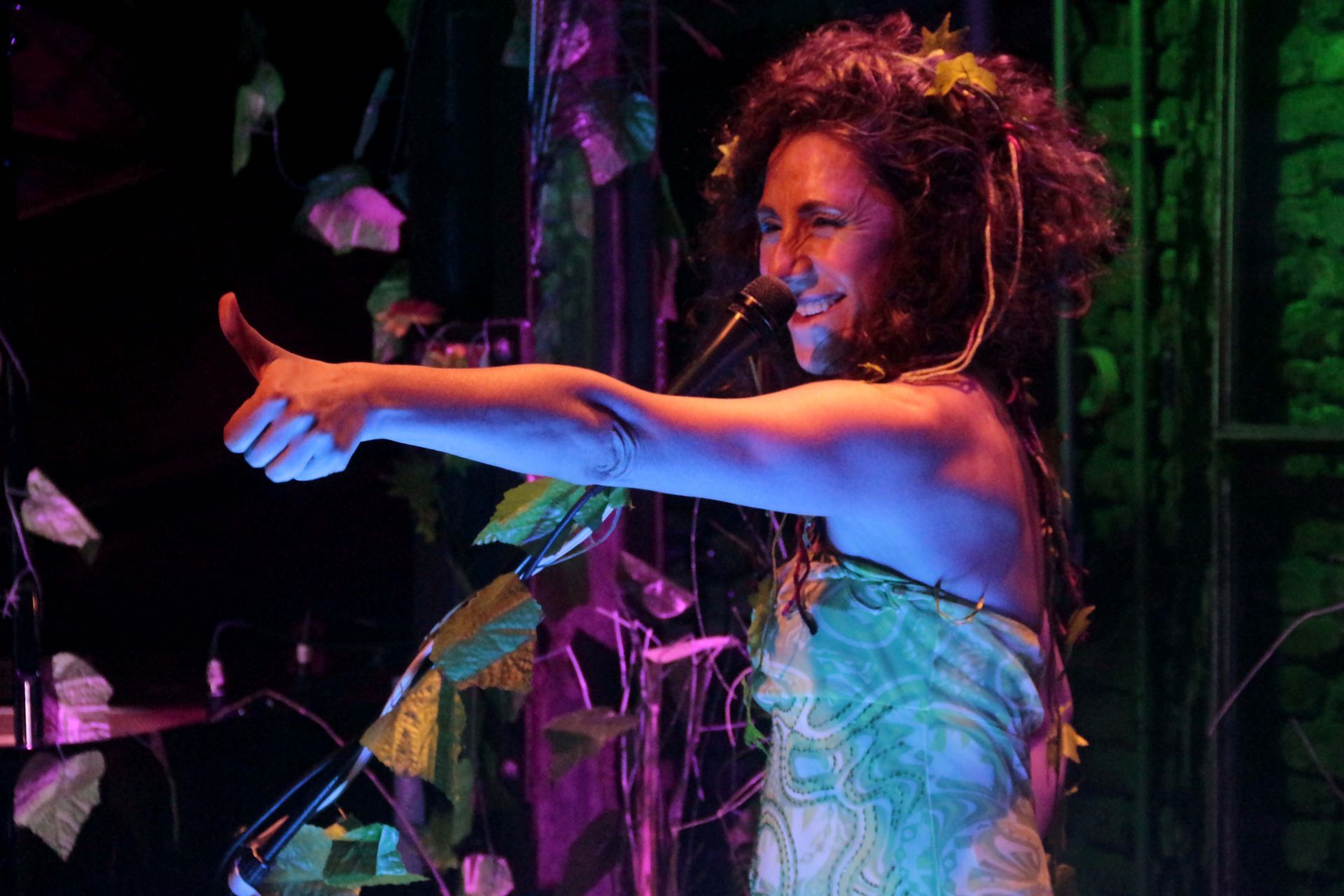 Una mujer con un traje de hojas en el escenario hace un gesto de aprobación con el pulgar hacia arriba.