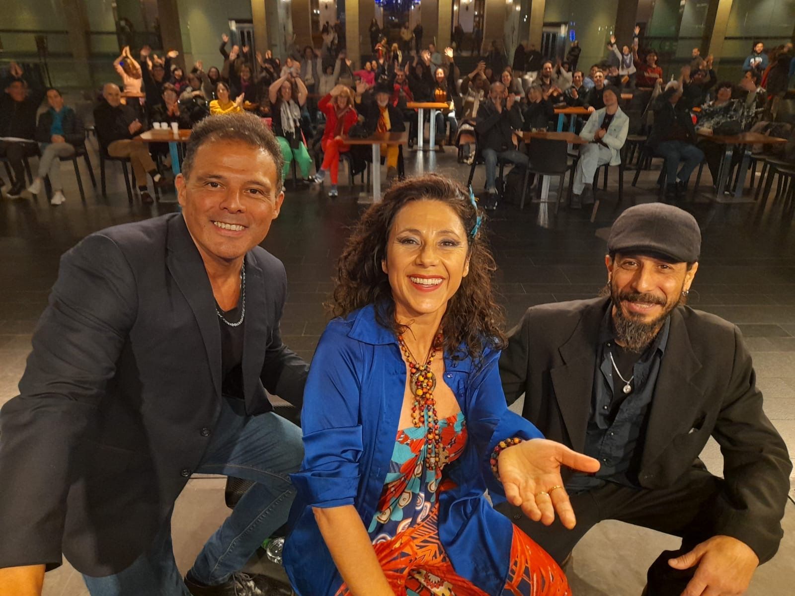 Tres personas posando para una foto con una multitud al fondo