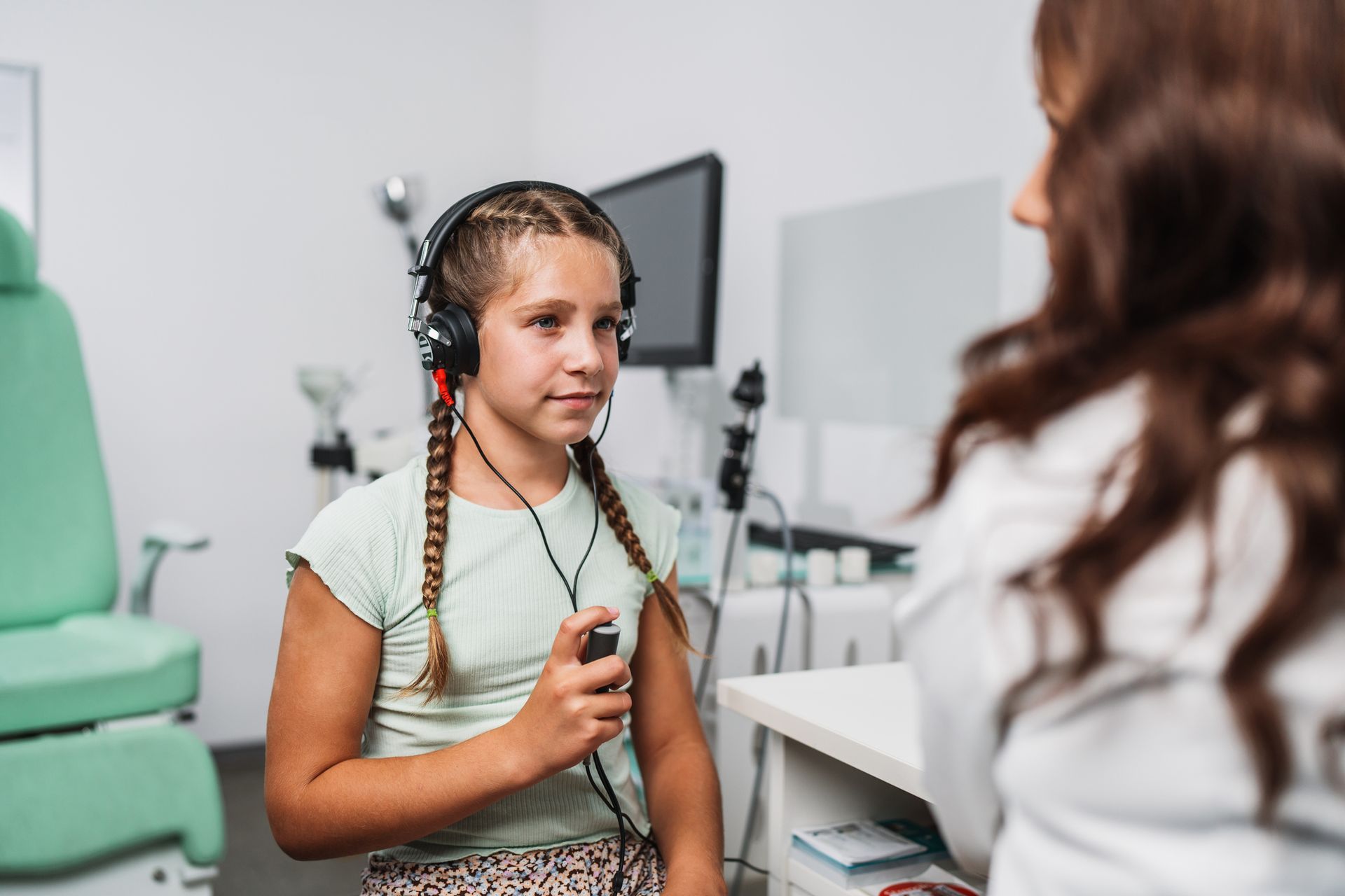 Girl in headphones undergoing a hearing test with a doctor in a medical office.