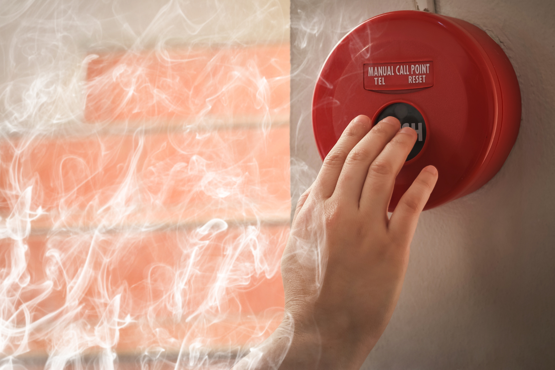 A red fire alarm is mounted on a white brick wall.