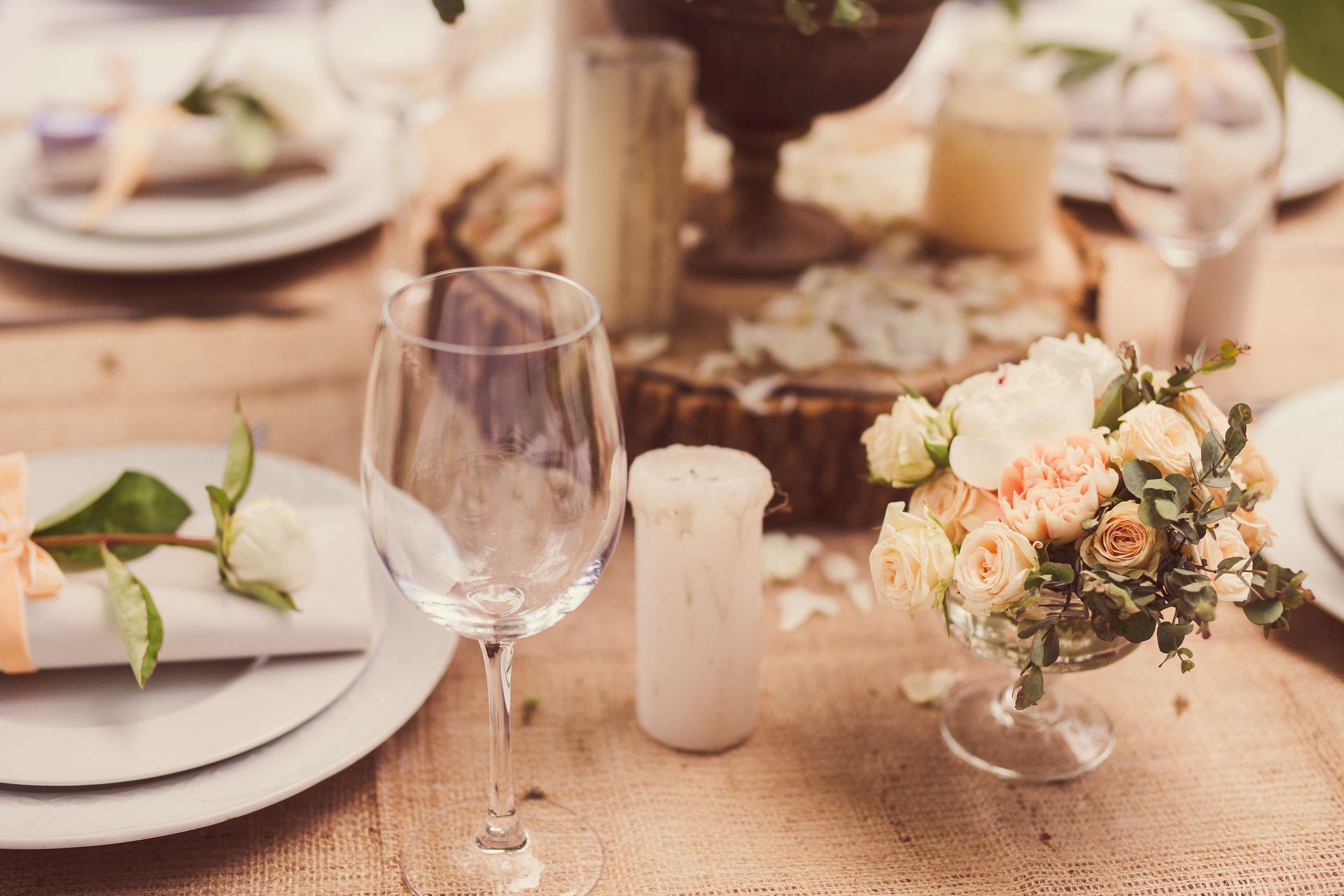 Elegante Tischdekoration mit Blumen, Tellern und einem Weinglas.