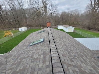 The roof of a house with a chimney and a lot of grass.