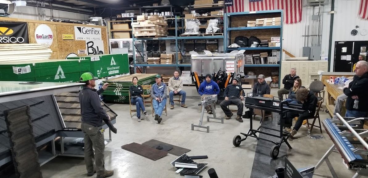 A group of people are sitting around a table in a warehouse.