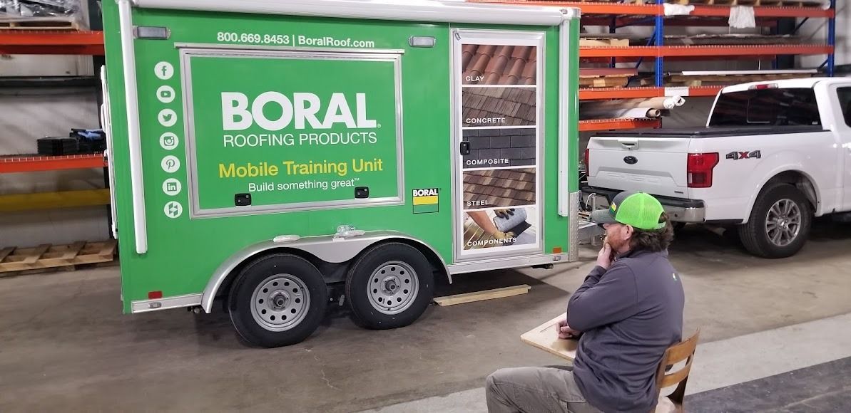 A man is sitting in front of a green trailer.