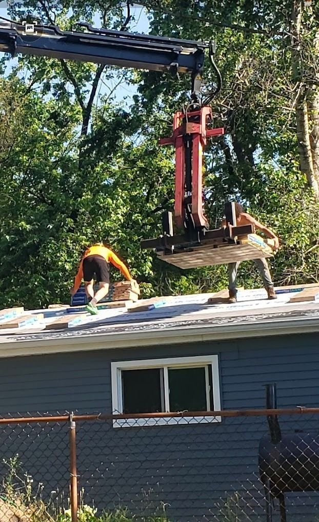 Two men are working on the roof of a house with a crane.