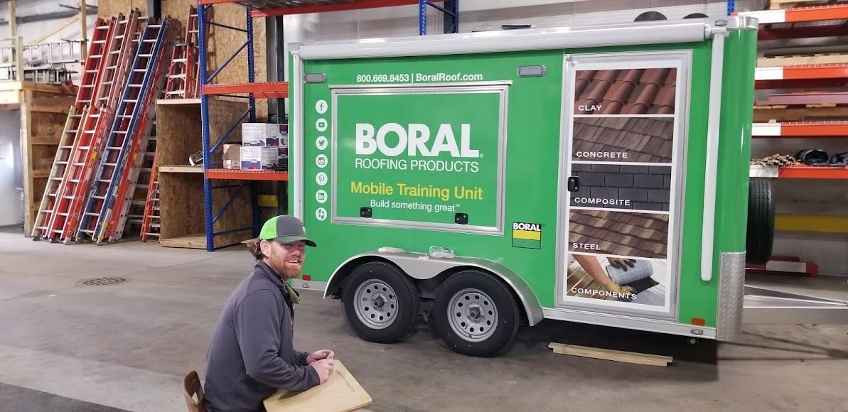 A man is pushing a green trailer with the word boral on it.