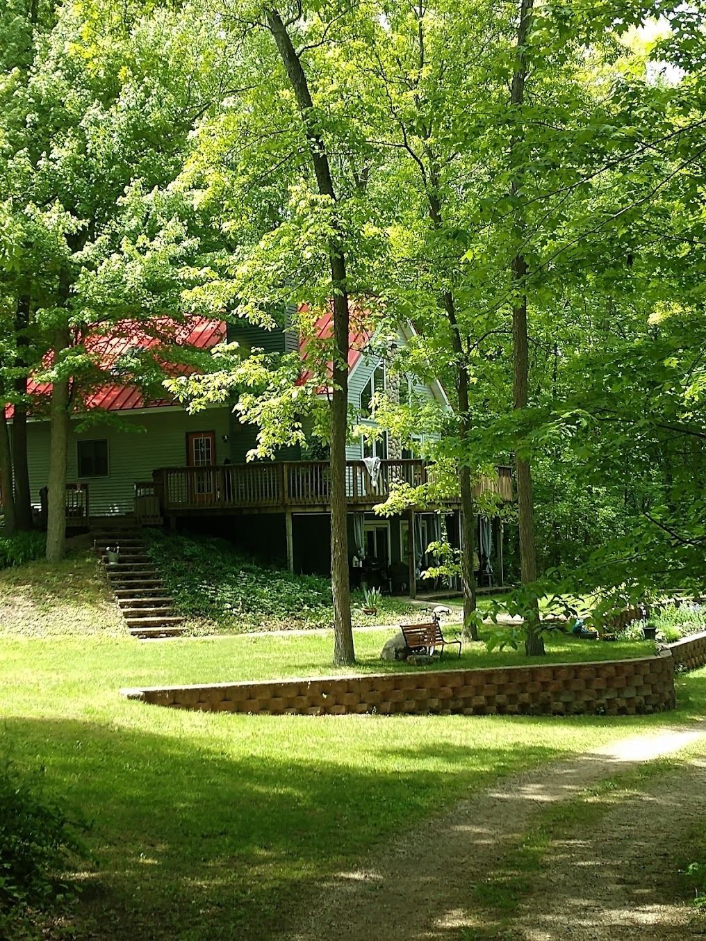 A house with a red roof is surrounded by trees and grass.