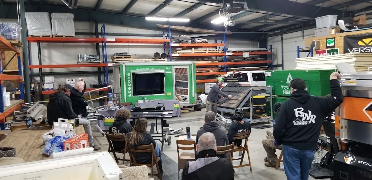 A group of people are sitting in chairs in a warehouse.