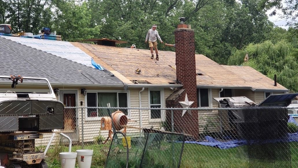 A man is standing on the roof of a house.