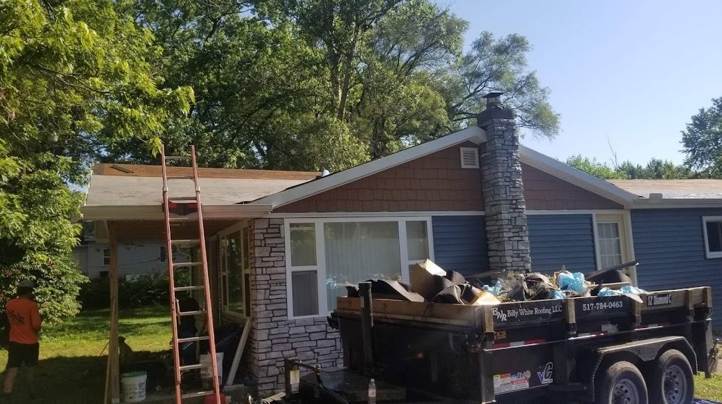 A house with a trailer full of trash in front of it.