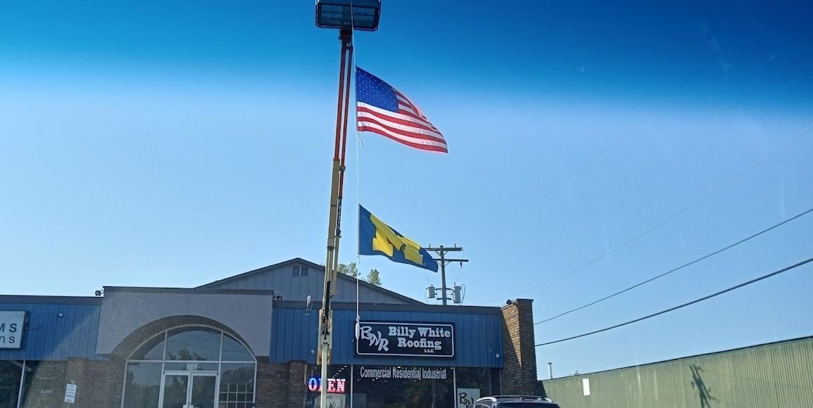 Two flags are flying in front of a building.