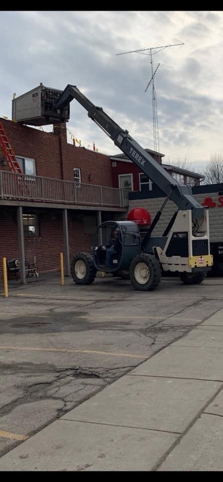 A crane is sitting in a parking lot next to a building.
