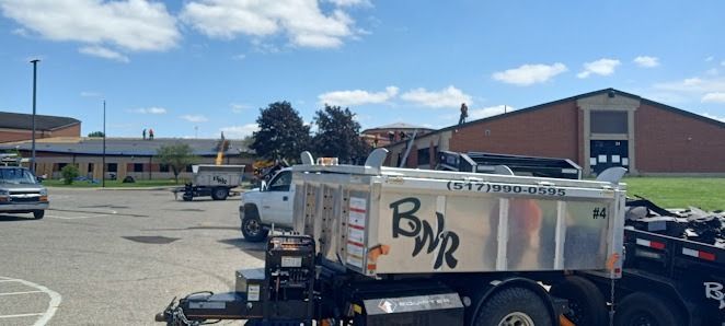 A dump truck is parked in a parking lot in front of a building.