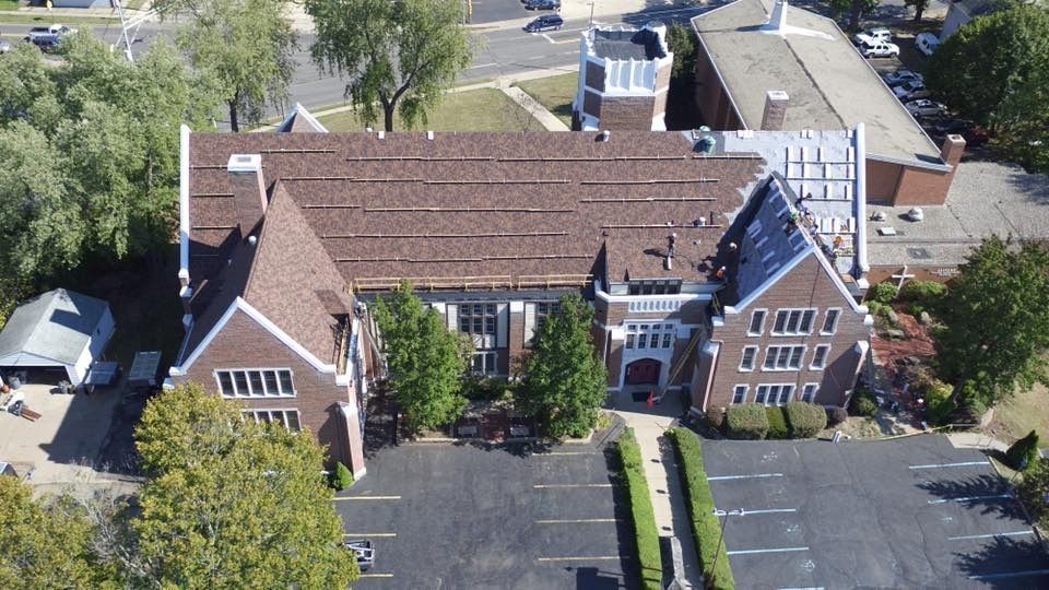 An aerial view of a large brick building with a parking lot in front of it