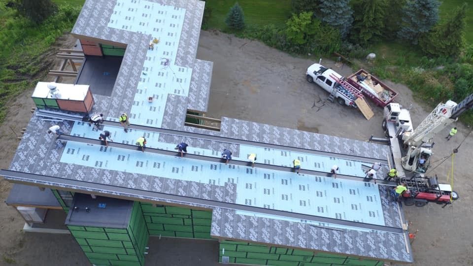An aerial view of a house under construction with workers on the roof.