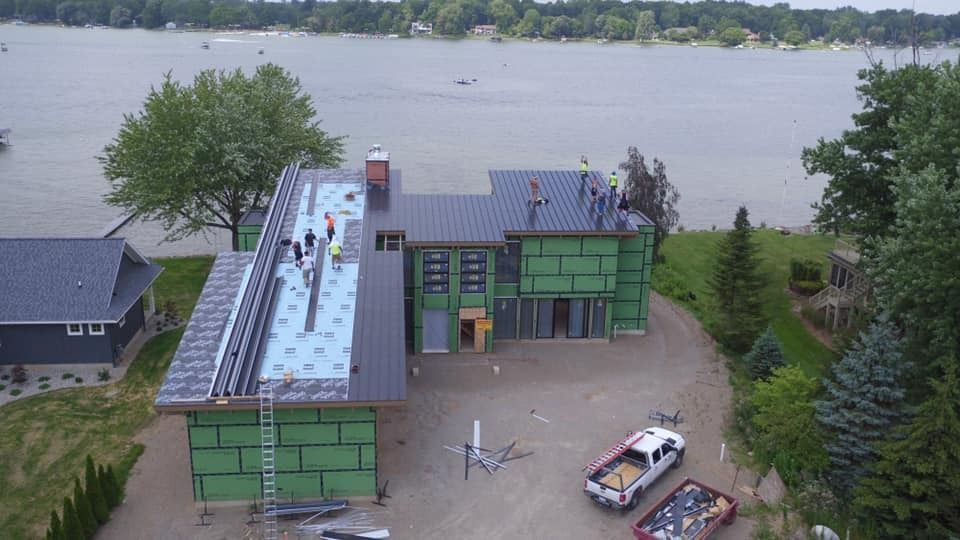 An aerial view of a house under construction next to a body of water.