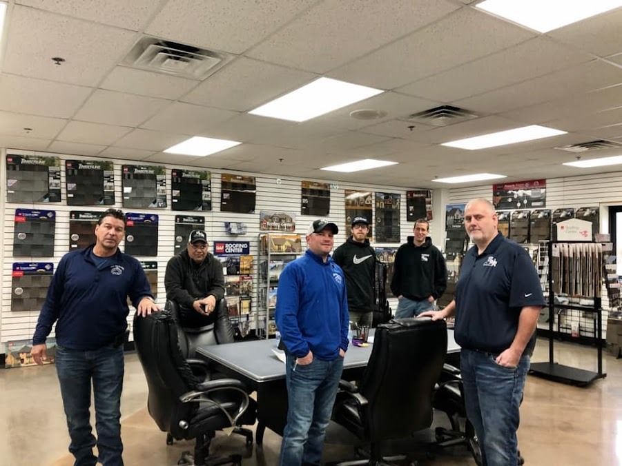 A group of men are standing in a room in front of a table.